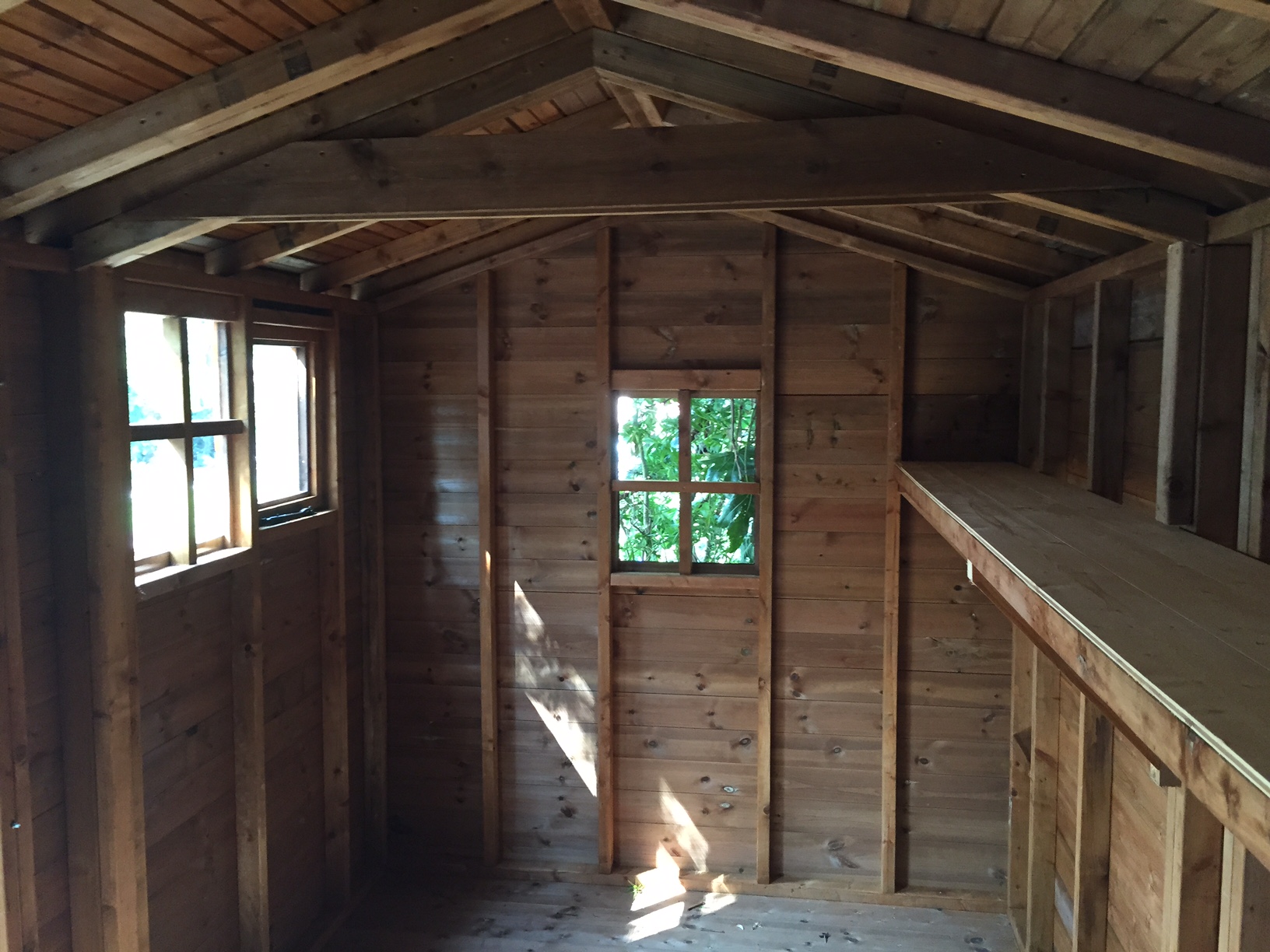 Interior of a bespoke timber shed showing shelving and roof structure