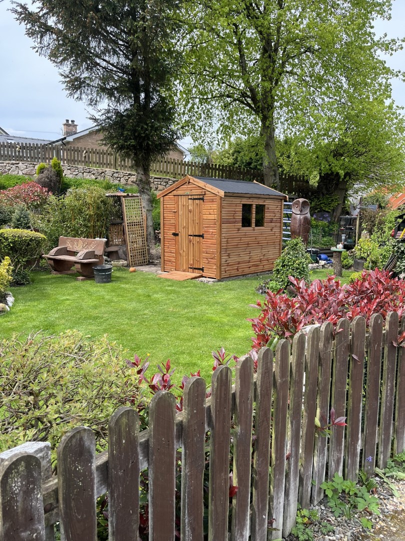 Wide garden view showing the 8 by 6 Beast shed set within a pristine landscaped garden